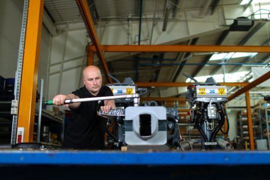 Dellner employee inspecting an automatic coupler for repair service in Poland